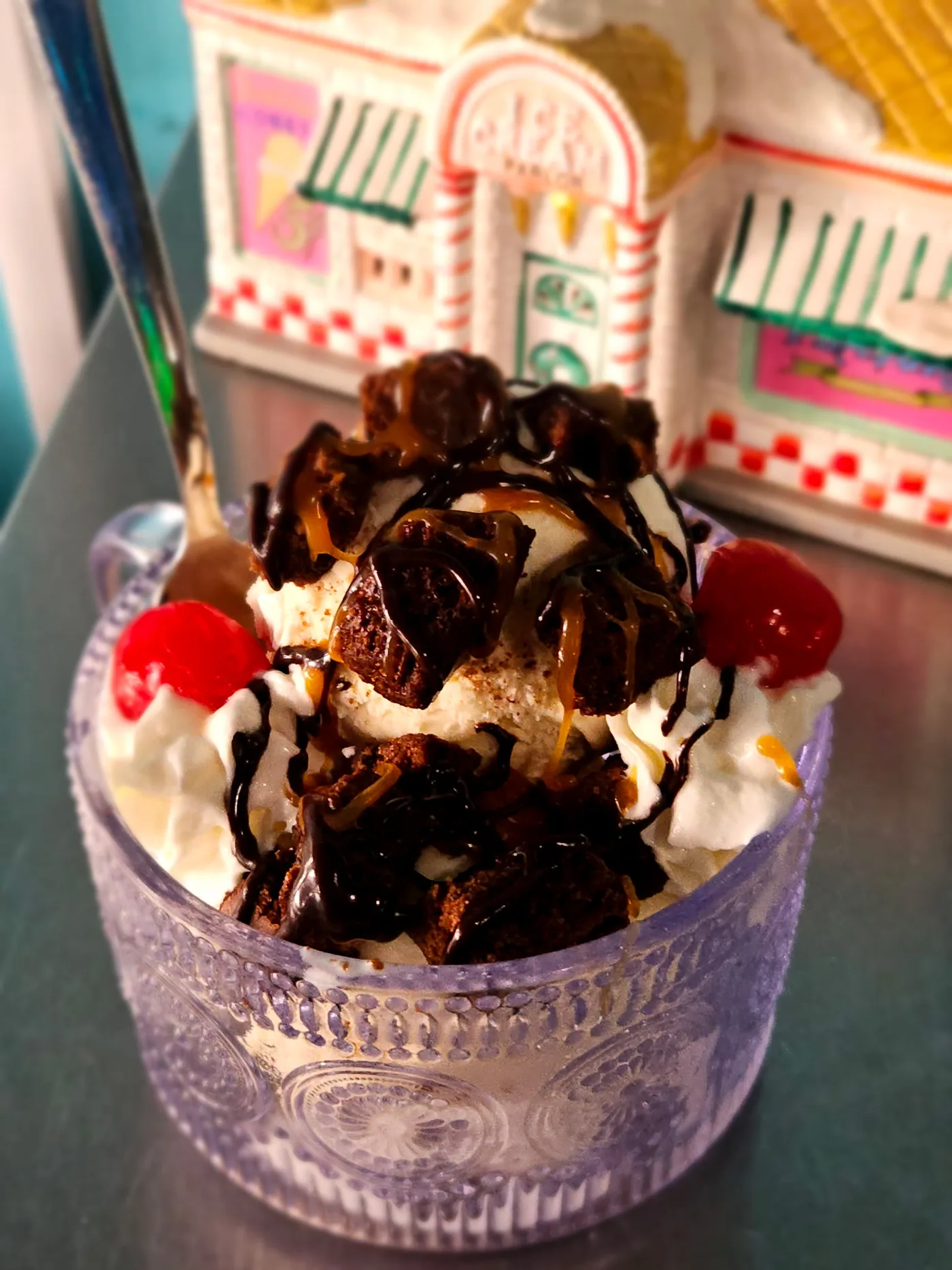 Classic sundae with brownie chunks, hot fudge, whipped cream, and two maraschino cherries, in a fluted glass coupe