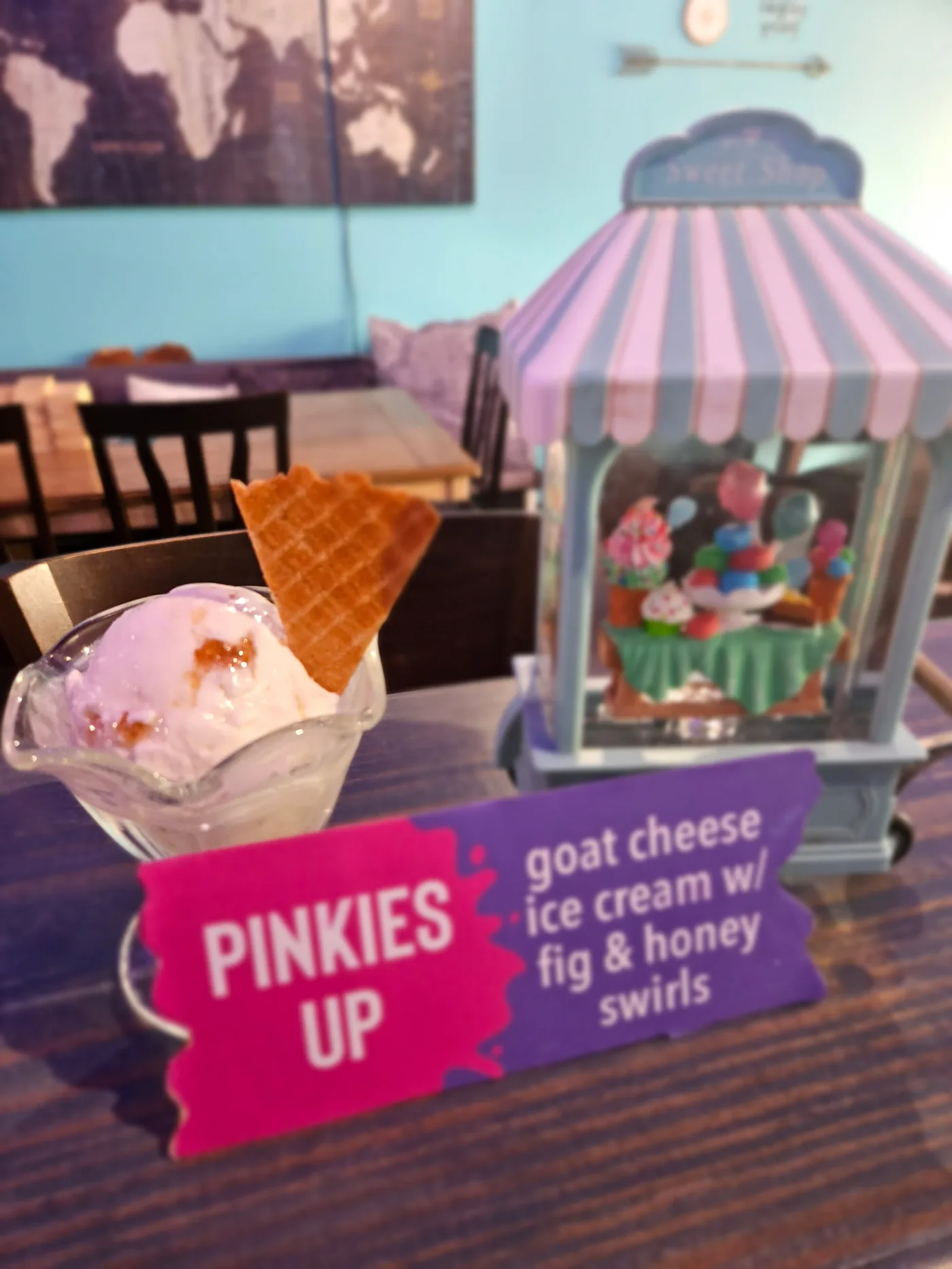 Pinkies Up — goat cheese ice cream with fig and honey swirls in a coupe with a waffle wedge, beside a Sweet Shop carousel decoration