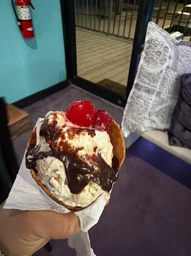 Waffle bowl with vanilla ice cream, chocolate sauce, and cherries